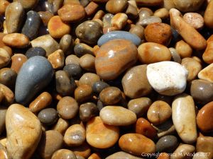 Colourful wet pebbles in the breaking waves at the waters' edge on the beach