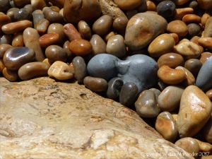 Colourful wet pebbles in the breaking waves at the waters' edge on the beach