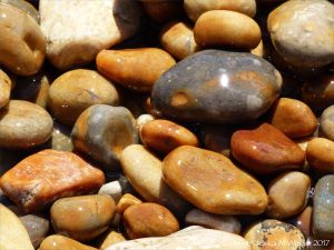 Colourful wet pebbles in the breaking waves at the waters' edge on the beach