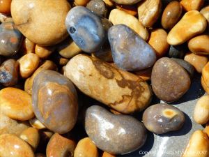 Colourful wet pebbles in the breaking waves at the waters' edge on the beach
