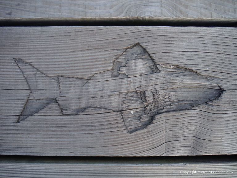 Fish carving in a wooden plank on a pier