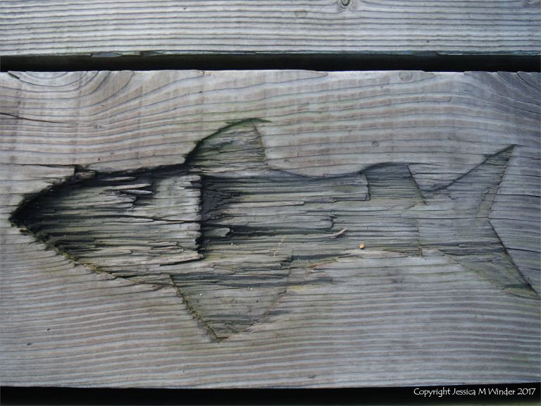 Fish carving in a wooden plank on a pier