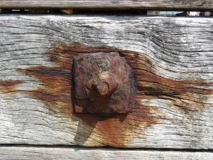 Rusty iron fitments on a wooden breakwater on the seashore