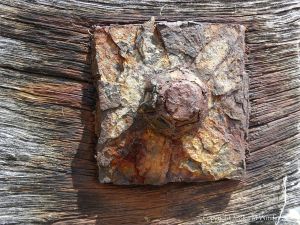 Rusty iron fitments on a wooden breakwater on the seashore