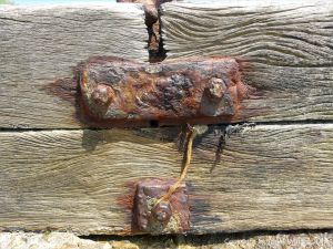 Rusty iron fitments on a wooden breakwater on the seashore