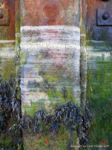 Lines of dried sea foam left by the receeding tide on a rusty pier