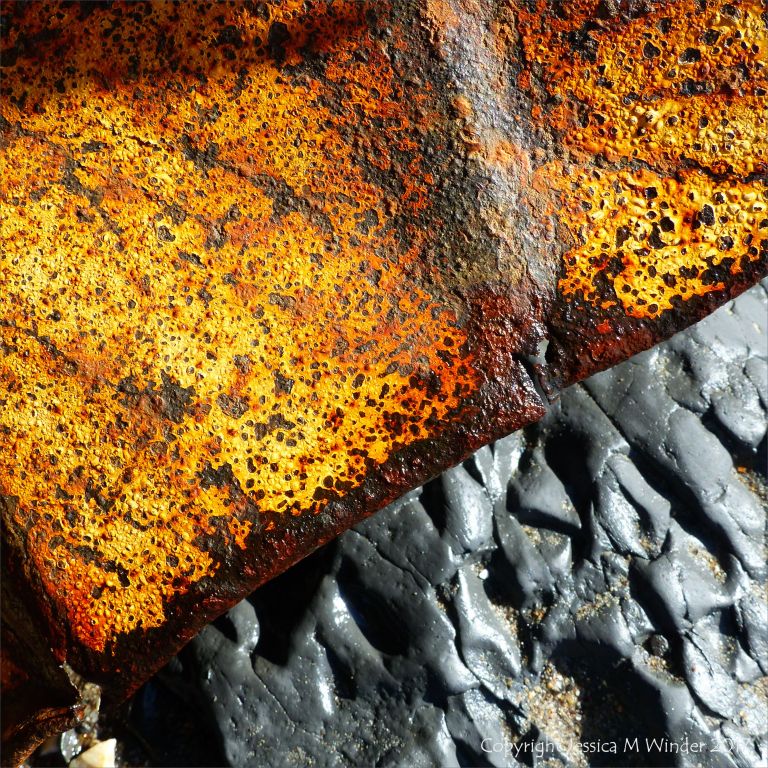 Rusty painted metal junk on the seashore with rocks