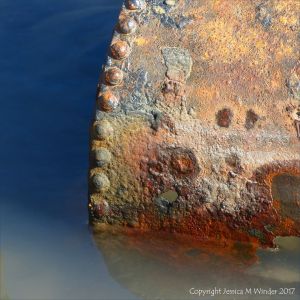 Rusty metal object in a tide pool on the beach