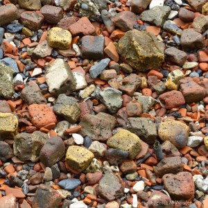 Detail of the composition of an urban shore along a tidal river where water-worn historical building and domestic debris is mixed with natural flints and stones.