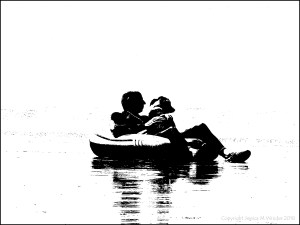 Black and white image of a man and his dog chilling out in an inflatable on the beach