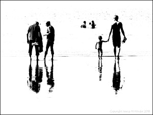 Black and white image of people on the water's edge at the beach