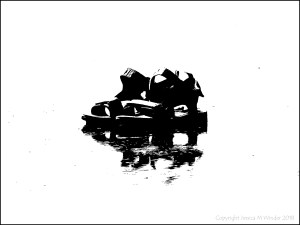 Black and white image of a pair of sandels on the wet sand at the beach
