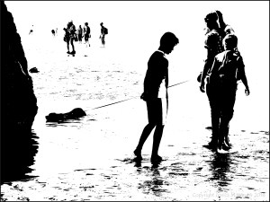 Black and white image of people with a dog in a tide pool