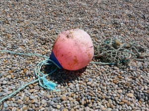 Red buoy washed up on a pebble beach