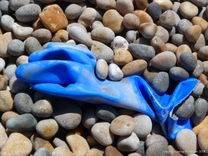 Blue plastic glove washed up on a pebble beach