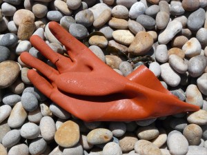 Orange plastic glove washed up on a pebble beach