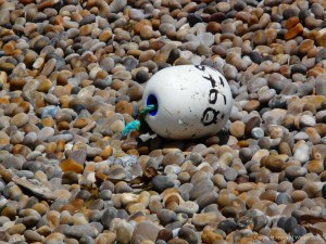 White fishing buoy washed up on a pebble shore