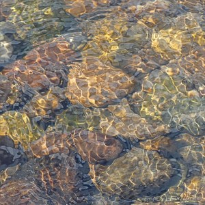 Natural patterns of reflected light on water flowing over pebbles