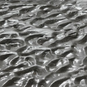 Close-up of natural ripple patterns in wet sand