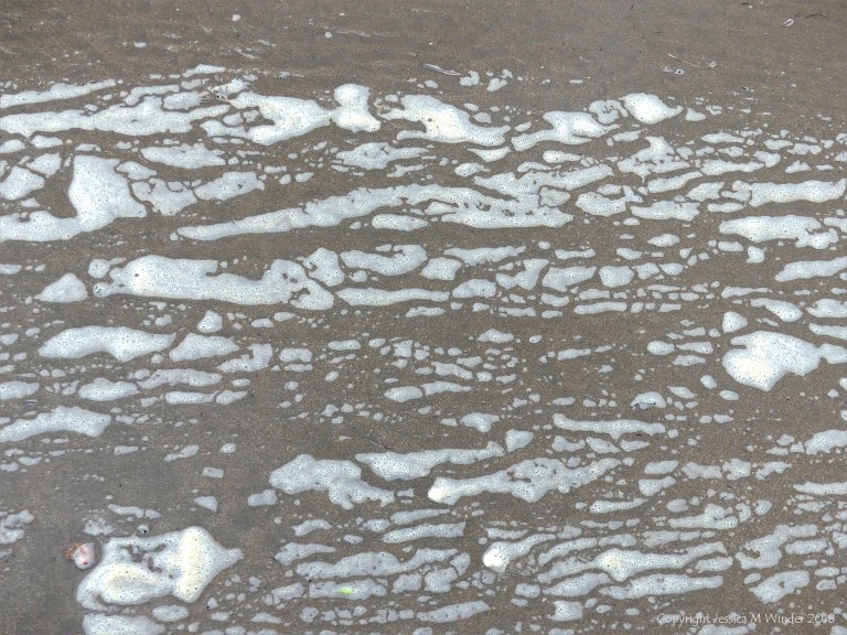 Natural patterns of sea foam on the beach