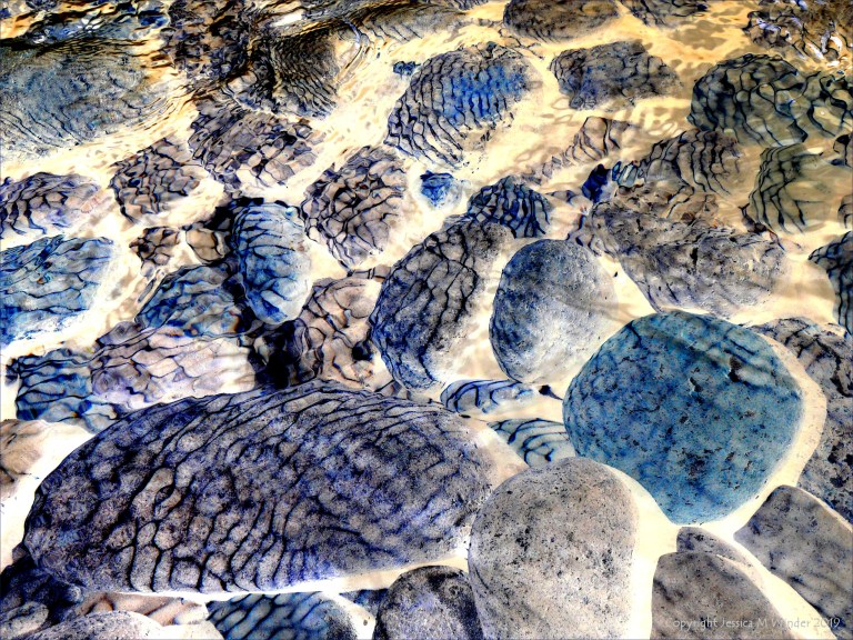 Natural patterns of reflected light on river-bed pebbles