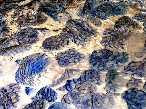Natural patterns of reflected light on river-bed pebbles