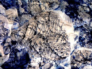 Natural patterns of reflected light on river-bed pebbles