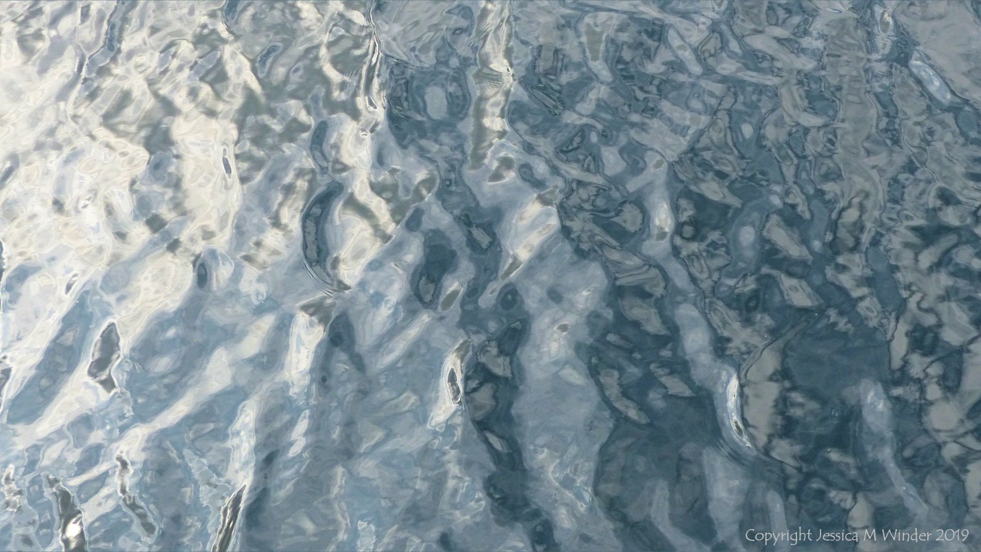 Rippled water reflecting clouds and sky