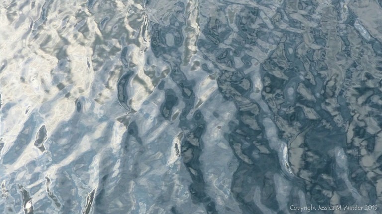 Rippled water reflecting clouds and sky