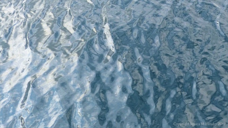Rippled water reflecting clouds and sky