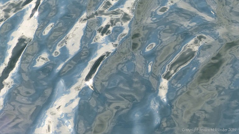 Rippled water reflecting clouds and sky