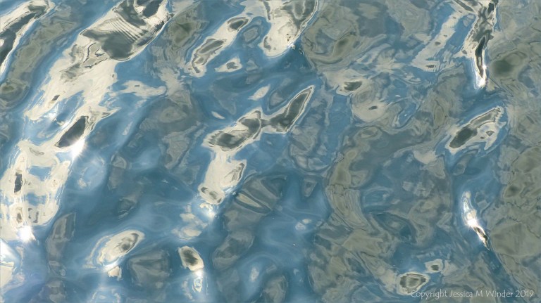 Rippled water reflecting clouds and sky