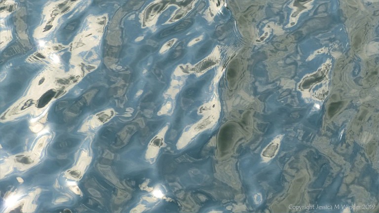 Rippled water reflecting clouds and sky