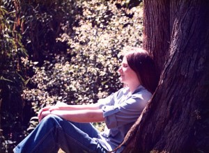 Woman sitting against a redwood tree