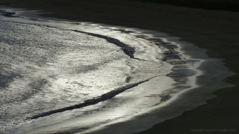 Beachscape with reflected dawn light on the sea