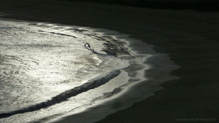 Beachscape with reflected dawn light on the sea