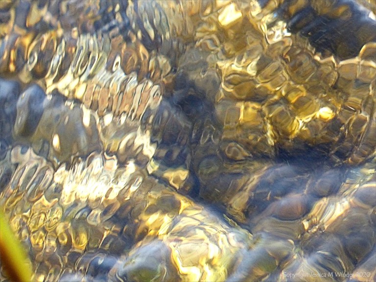 Abstract natural patterns of reflected light on flowing rippled water