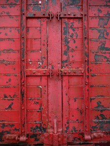 Flaking red paint on a piece of wooden agricultural equipment