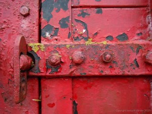 Flaking red paint on a piece of wooden agricultural equipment