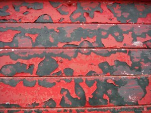 Flaking red paint on a piece of wooden agricultural equipment
