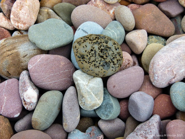 Large pebbles of different rock types on the beach