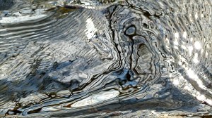Intricate changing patterns of reflected light on fast flowing water