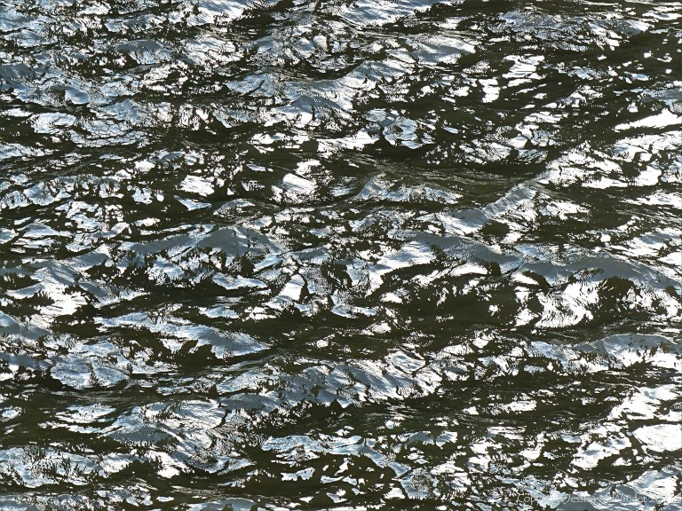 Natural abstract patterns of light reflected on flowing water