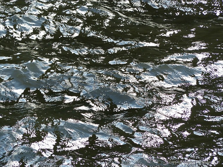 Abstract patterns of light reflected on the surface of flowing water