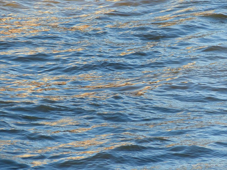 Golden reflected light on water in deep flowing river