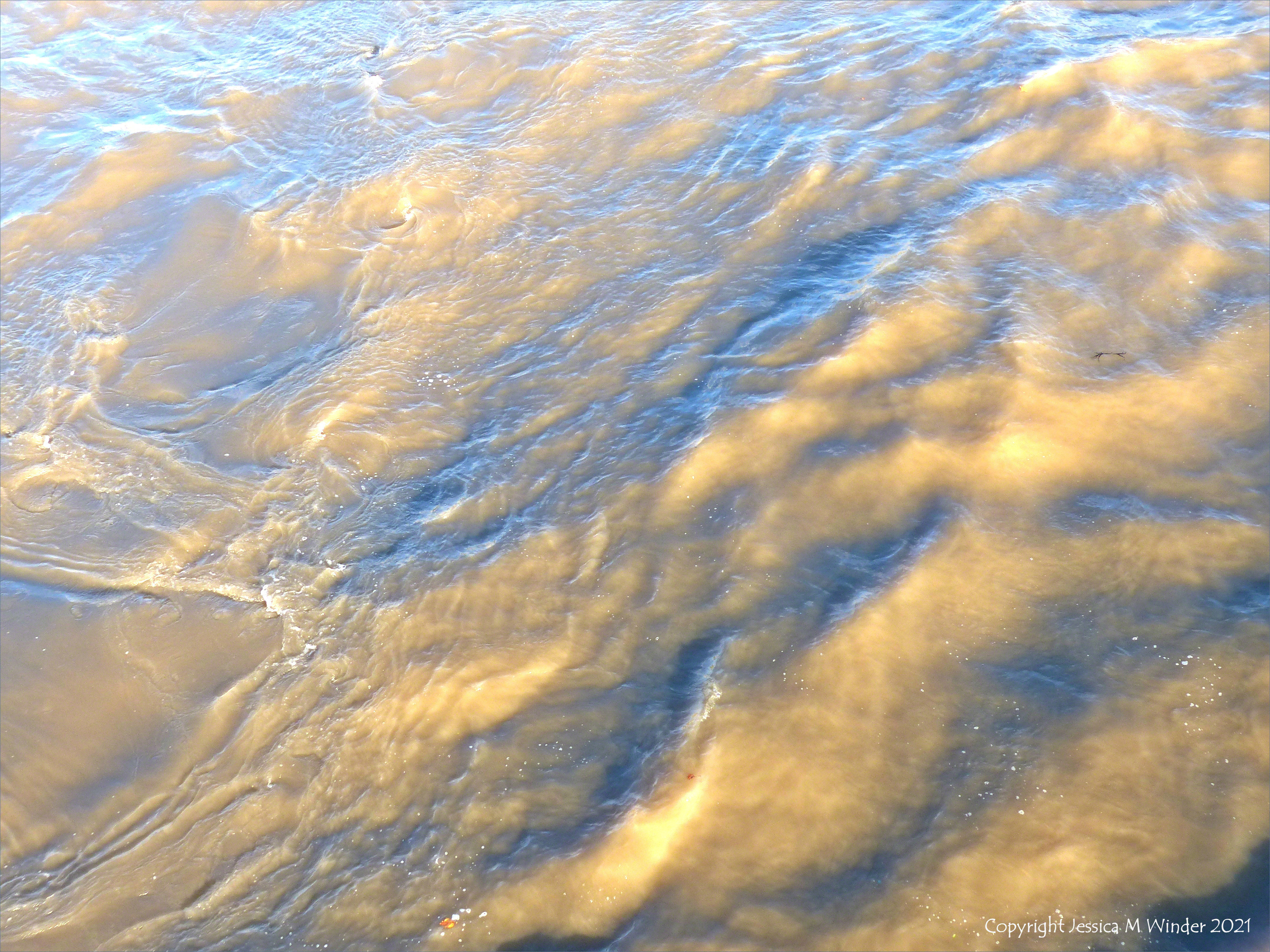Swirling river water immediately water downstream of a bridge