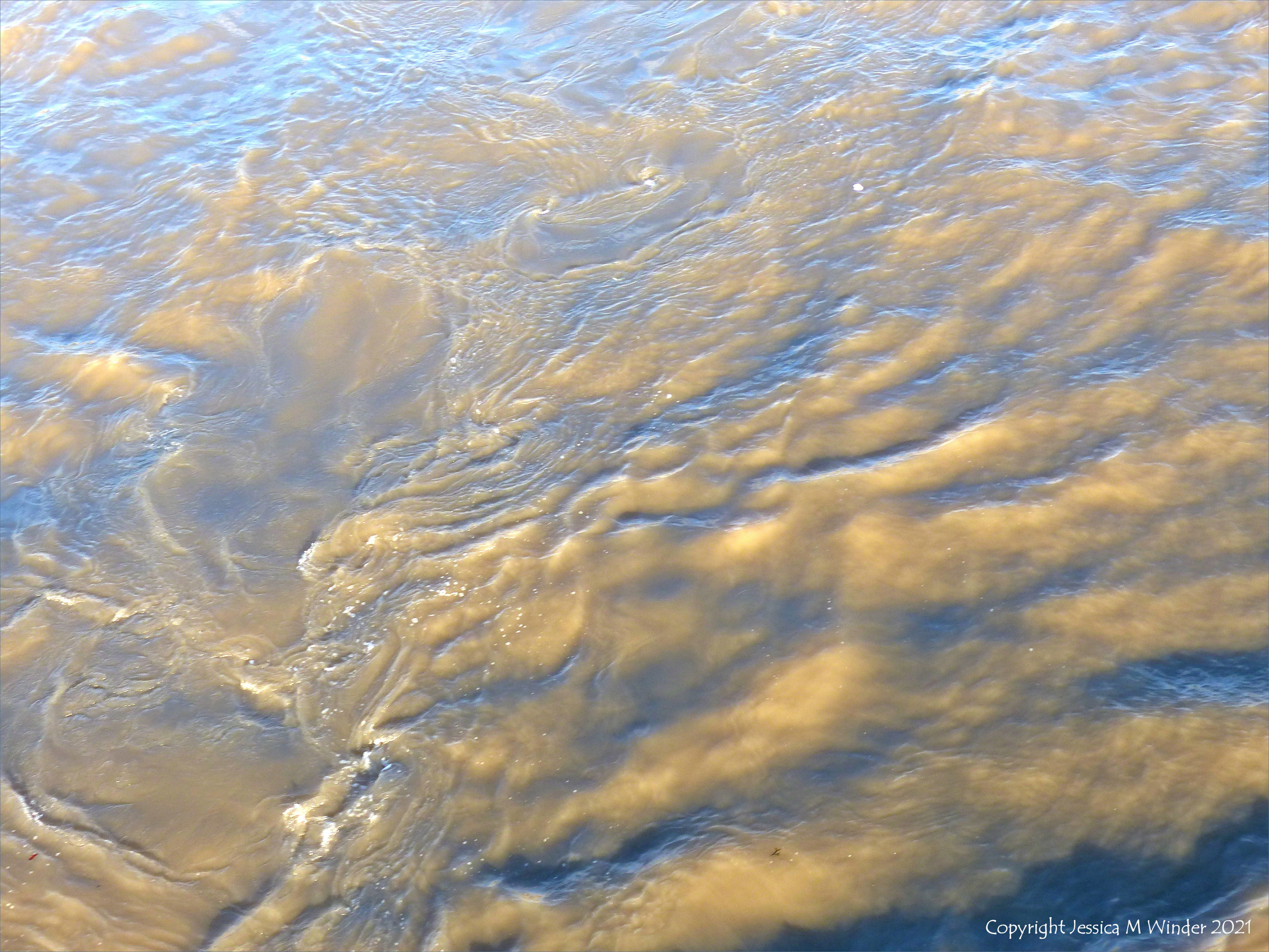 Swirling river water immediately water downstream of a bridge
