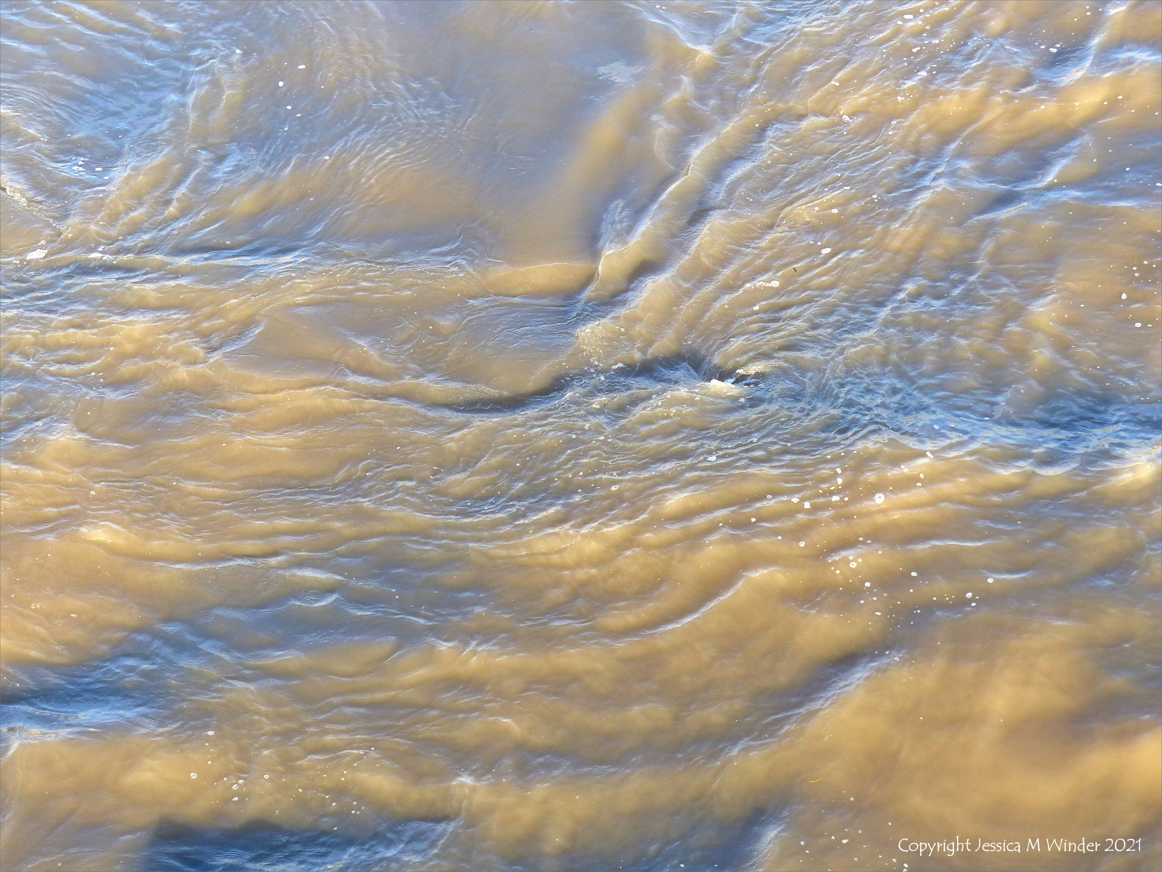 Swirling river water immediately water downstream of a bridge