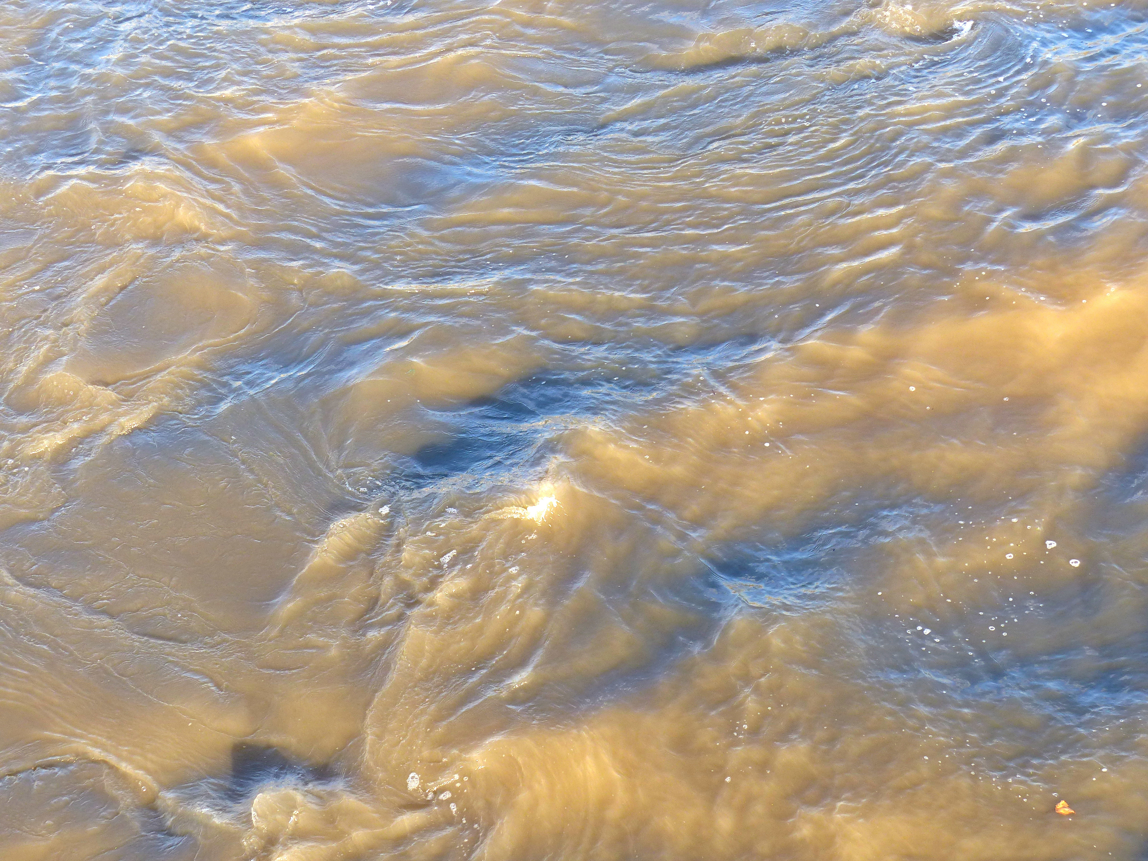 Swirling river water immediately water downstream of a bridge