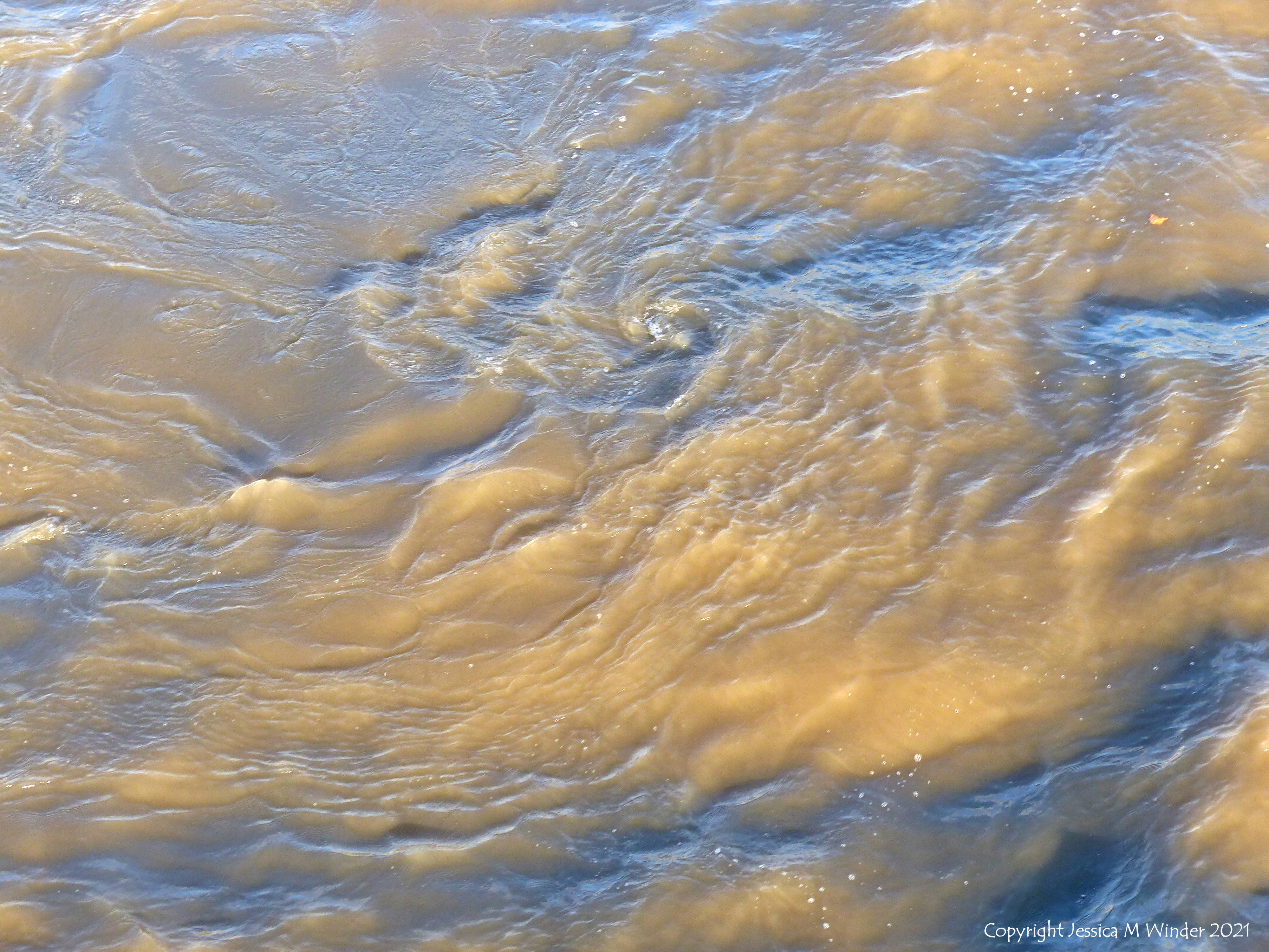 Swirling river water immediately water downstream of a bridge